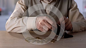 Pensioner putting coins into wallet, poverty concept, low social welfare