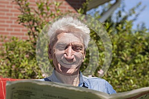 Pensioner reading amused newspaper