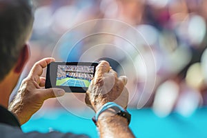 Pensioner records video of exciting match using smartphone. Passionate fan captures memorable moments enjoying game of