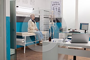 Pensioner senior woman standing alone in hospital office waiting for sickness expertise