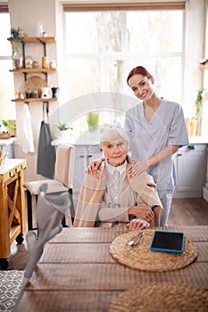 Beautiful pensioner sitting near caregiver