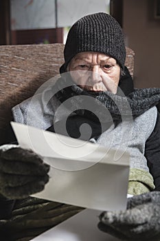 Pensioner is sitting with winter clothes indoors