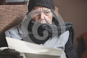 Pensioner is sitting with winter clothes indoors