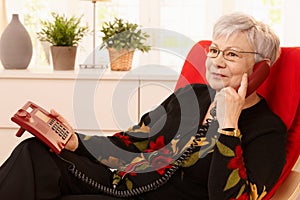 Pensioner woman using landline phone photo