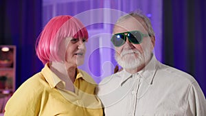 pensioners party, stylish old woman kisses the cheek of an elderly man in glasses with a gray beard, smiling and looking