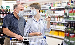 Pensioners in protective masks choose alcoholic beverages in supermarket