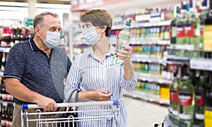 Pensioners in protective masks choose alcoholic beverages in supermarket