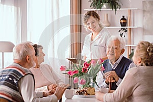 pensioners at retirement home talking during an afternoon snack photo
