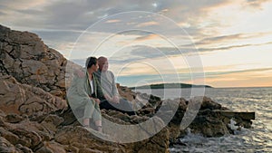 pensioners travel, joyful old man and his wife enjoy their vacation sitting on seashore backdrop of sunset