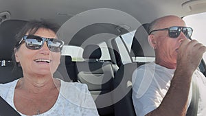 pensioners on vacation, happy elderly married couple driving in a car on the road during a trip