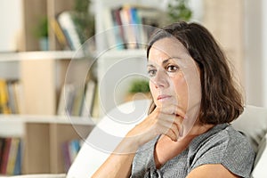 Pensive adult woman looking away sitting at home