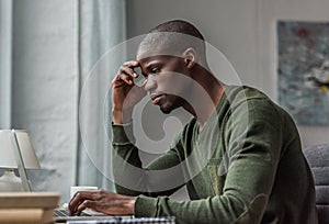 Zamyslený americký muž prenosný počítač zatiaľ čo pracovné 