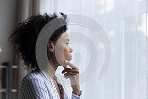 Pensive African American woman look in window thinking