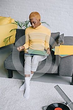 Pensive african american woman sitting with vinyl records in