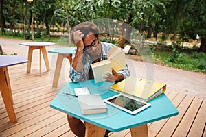 Pensive african young man reading and studying