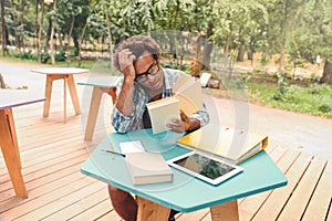 Pensive african young man reading and studying