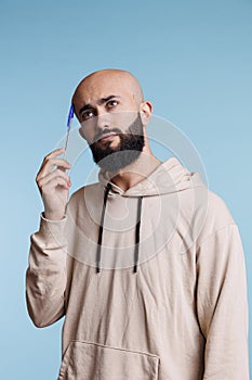 Pensive arab man holding pen to head