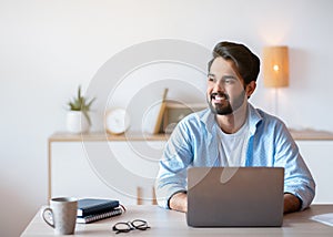 Pensive Arab Man Sitting At Desk With Laptop In Home Office
