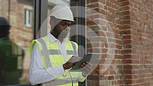 Pensive architect working on tablet near construction site