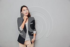 Pensive asian business woman with arm in pocket holding chin