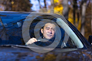 A pensive Asian man is sitting in the car, the driver is waiting and sad