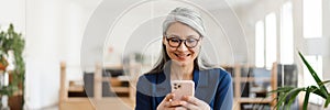 The pensive Asian woman holding a phone in her hands in the office