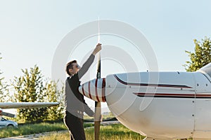 Pensive attrative young man pilot standing near small aircraft