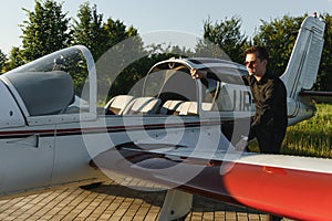Pensive attrative young man pilot standing near small aircraft