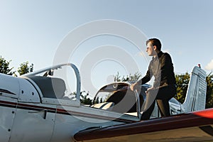 Pensive attrative young man pilot standing near small aircraft