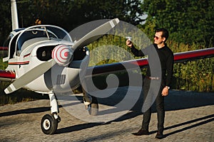 Pensive attrative young man pilot standing near small aircraft