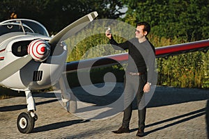 Pensive attrative young man pilot standing near small aircraft