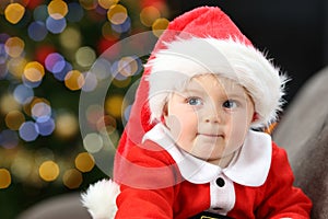 Pensive baby wearing santa costume in christmas