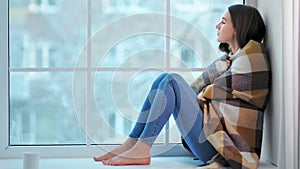 Pensive barefoot woman shrink from cold and bundle up warmer on plaid