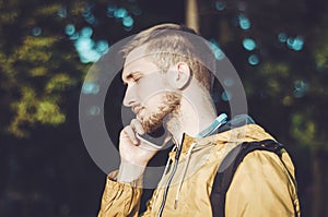 Pensive bearded man talking on smartphone and listen attentively. Young casual european male in yellow jackets, call