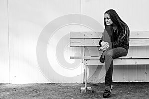 Pensive beautiful girl with long hair sitting on bench