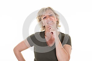 Pensive beautiful senior woman smiling hand over chin looking happy face cute smile posing in white wall background