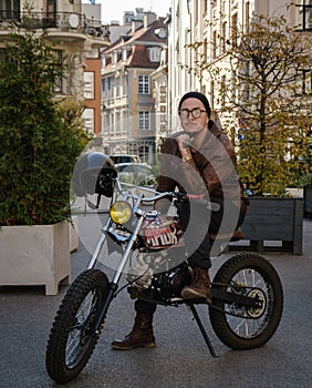 Pensive biker with glasses and oldfashioned motorcycle outdoors