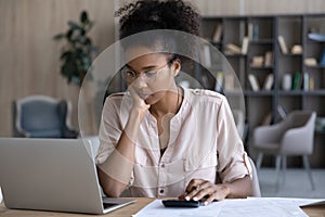 Pensive biracial woman manage budget on laptop at home