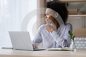 Pensive biracial woman work on computer making plans