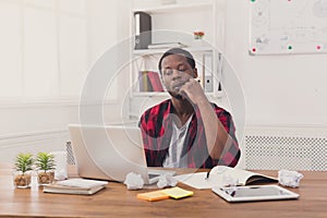 Pensive black businessman in casual office, work with laptop