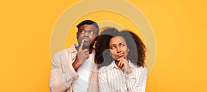 Pensive black couple in casual wear on yellow backdrop