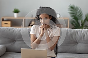 Pensive black girl busy thinking working on laptop