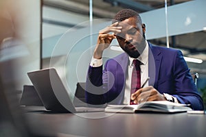 Pensive black man CEO working at office, taking notes