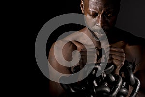 Pensive black man holding large heavy chains. photo