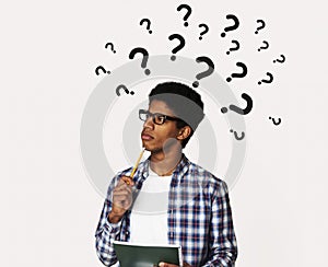 Pensive black man with question marks over his head deep in thought, solving business problem, creative collage