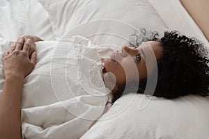 Pensive black woman lying in bed suffering from insomnia