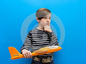 Pensive boy with an airplane in his hands. A boy of 9 years plays a pilot. Children`s hopes and dreams. Opening of a children`s