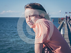 Pensive boy on a pier at baltic sea