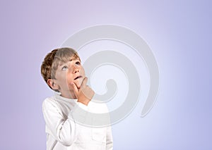 Pensive boy portrait looking up on empty lilac background