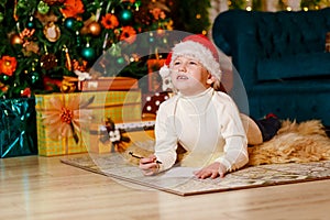 Pensive boy in Santa`s red cap writes a letter to Santa Claus for Christmas . dreams